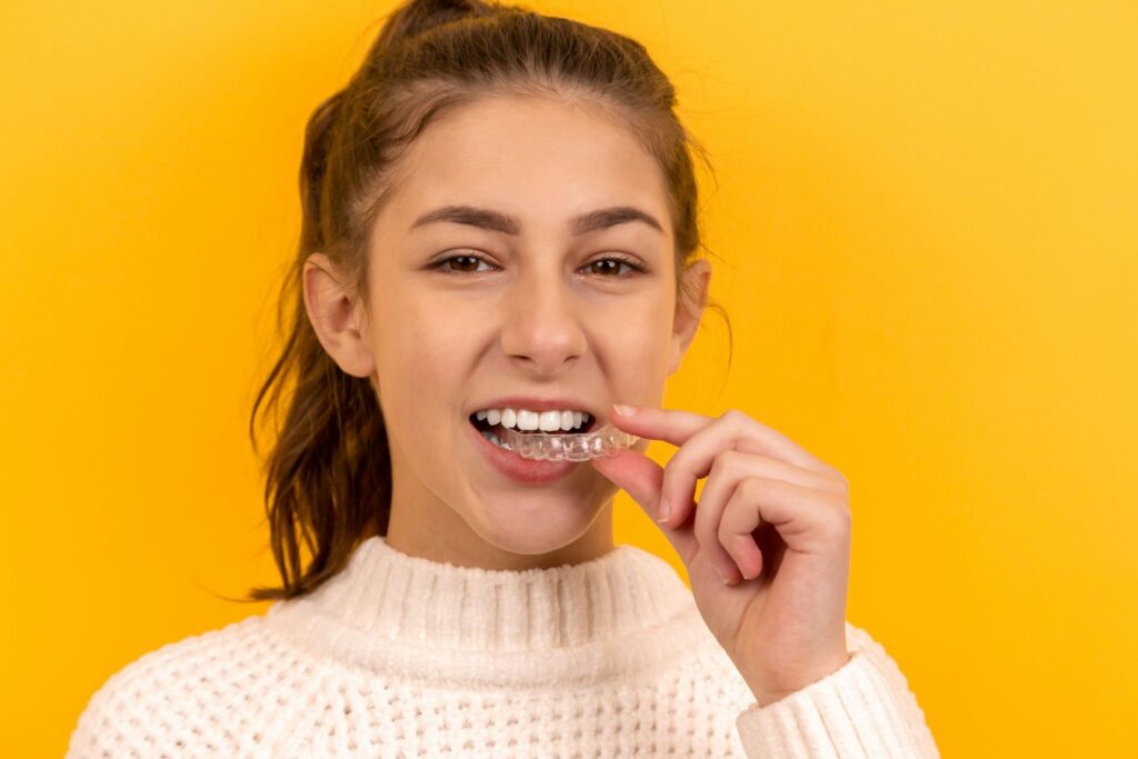 Mujer joven usando alineadores Invisalign, alternativa moderna a los brackets